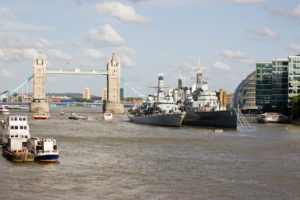 View of the River Thames from London Bridge, City of London. Tower Bridge in the background with the naval ships HMS Portland and HMS Belfast moored towards the centre.