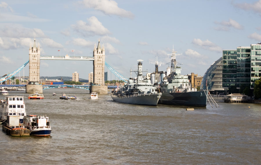 View of the River Thames from London Bridge, City of London. Tower Bridge in the background with the naval ships HMS Portland and HMS Belfast moored towards the centre.